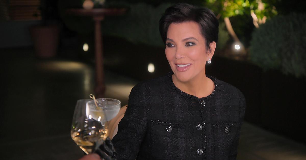 Kris Jenner, wearing an all-white ensemble, smiles and holds out her wine glass in Season 5 of 'The Kardashians.'